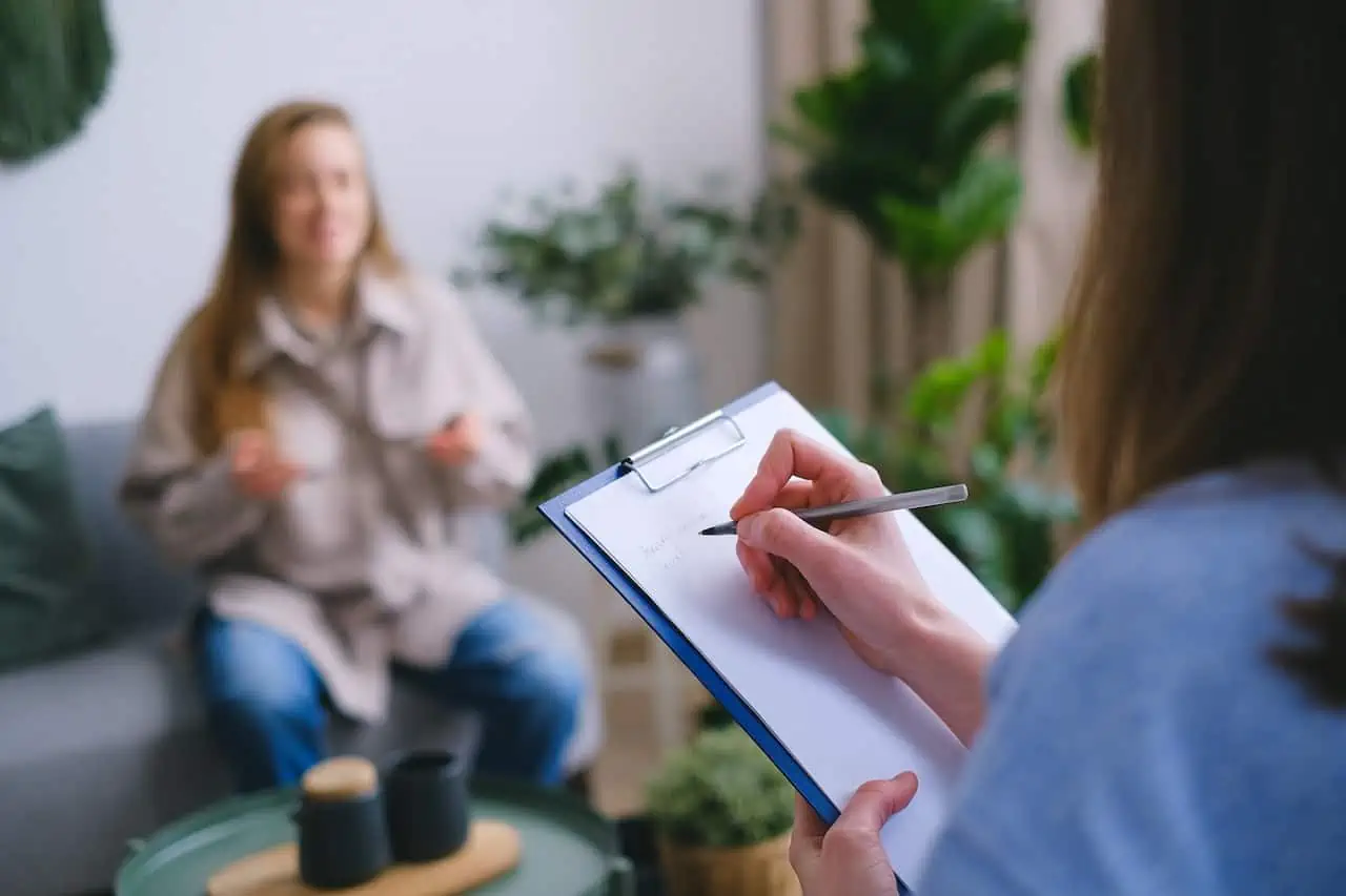 person writing notes on a clipboard about a patient